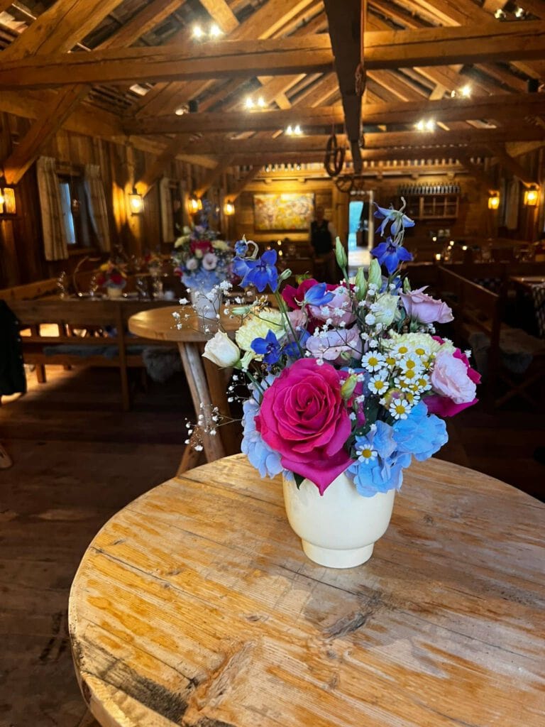 Blumenstrauß mit Rosen, Hortensien und Gänseblümchen in rustikaler Vase.
