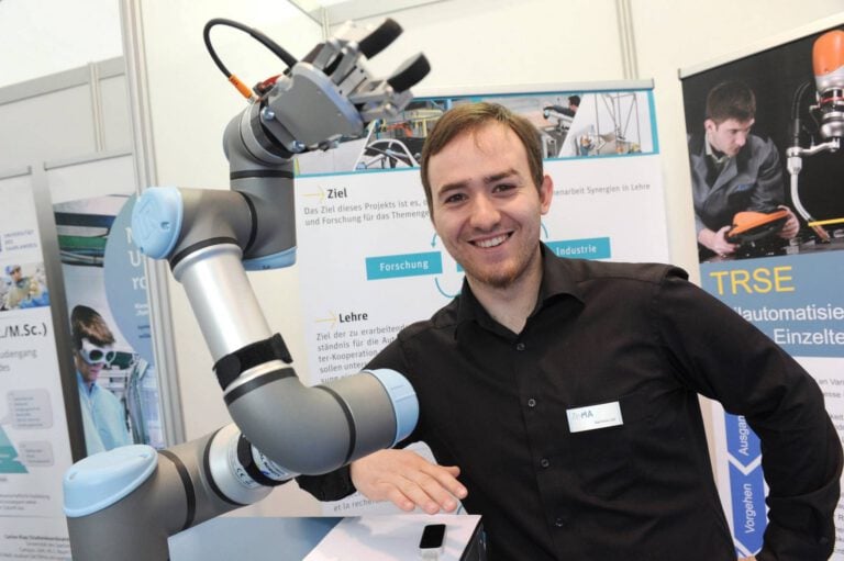 Mann mit Roboterarm bei PURA Erlebnismanufaktur auf Jobmesse.