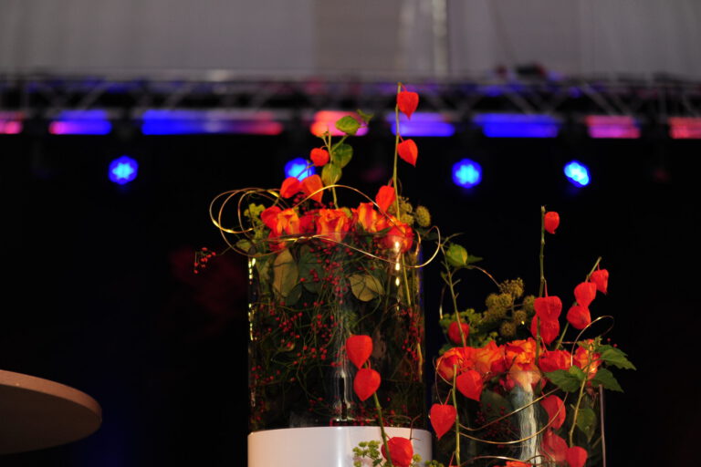 Kunstvolle Blumenarrangements bei einer Firmenveranstaltung.