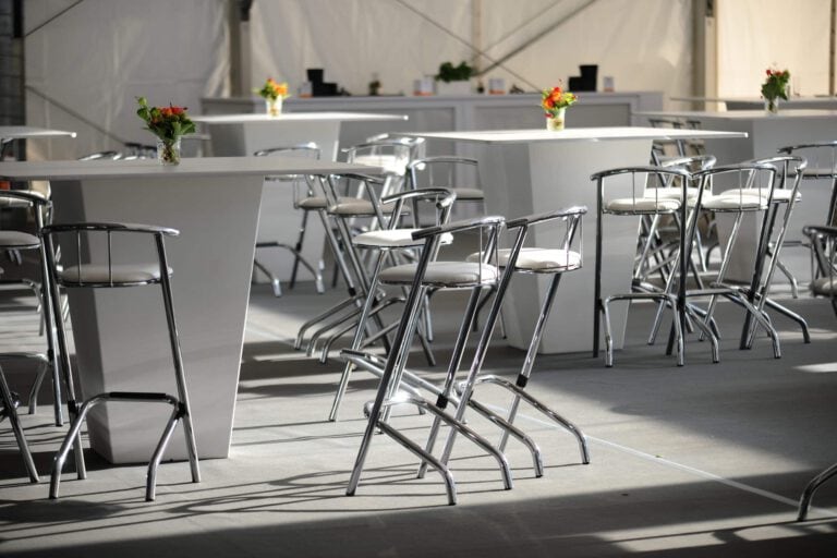 Moderne Eventlocation mit Stehtischen und Blumenarrangements.