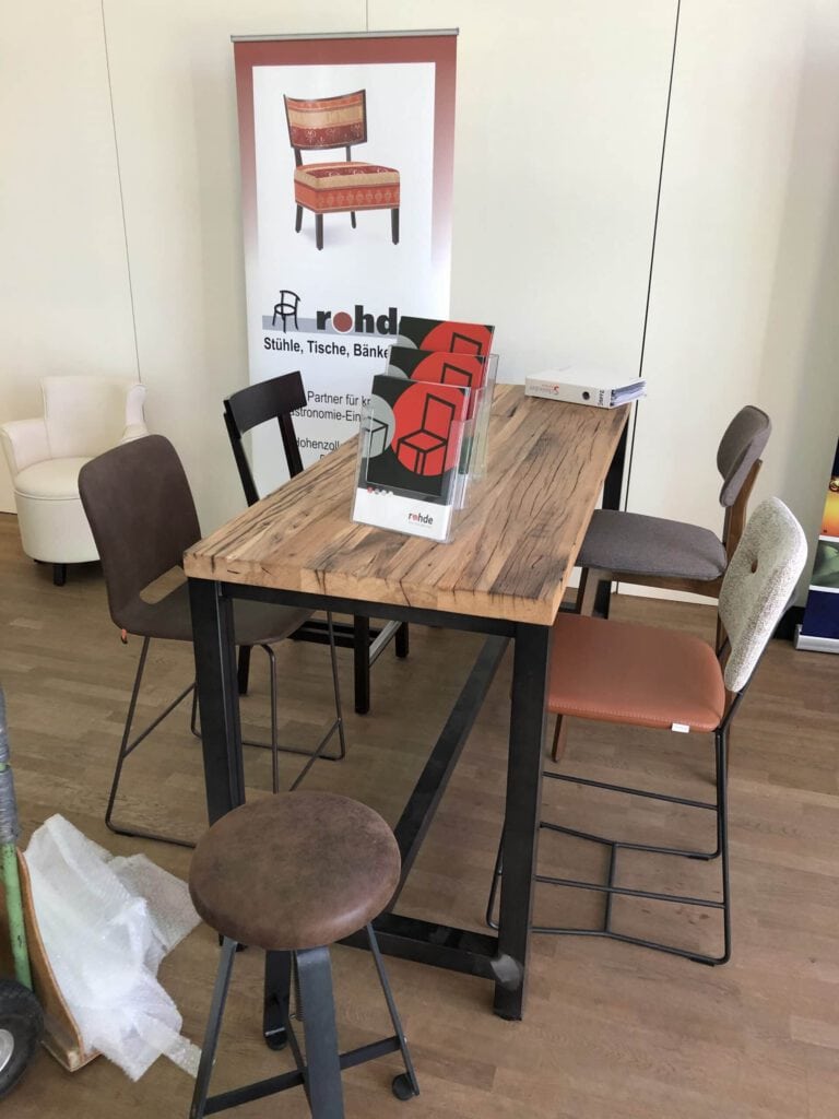 Verschiedene Stühle um einen Holztisch bei der Messe DEHOGA Marktplatz.