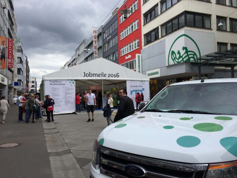 Outdoor-Jobmesse 2016 auf einer Stadtstraße mit Besuchern und Zelt.