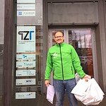 Mann in grüner Jacke vor Firmengebäude bei Roadshow-Veranstaltung.