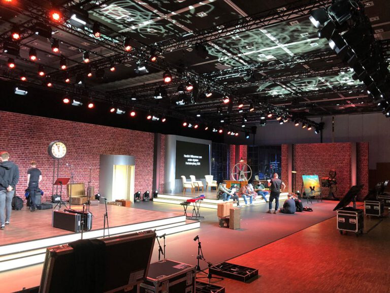 Modernes Eventstudio mit Bühne, Technik und Sitzgelegenheiten.