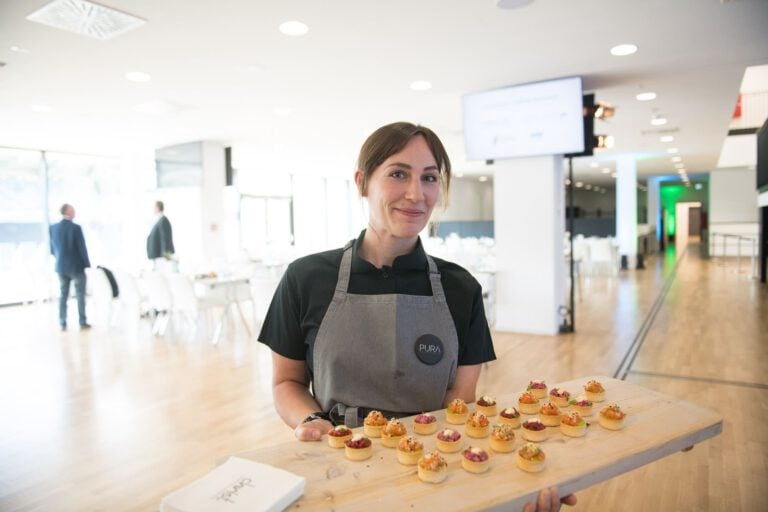 Frau präsentiert kreative Cupcakes im modernen Veranstaltungsraum.
