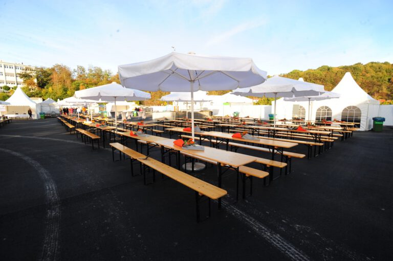 Große Outdoor-Veranstaltung mit Tischen und Sonnenschirmen bei PURA Erlebnismanufaktur.