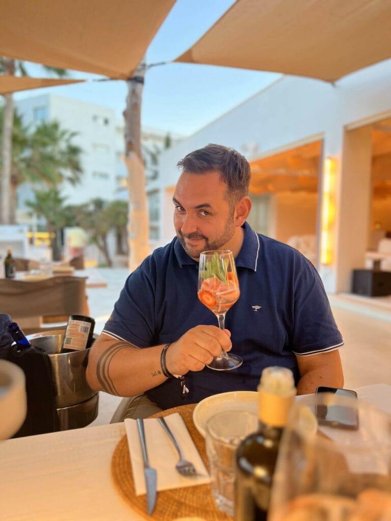 Mann mit Drink in einem Restaurant im Freien bei PURA Erlebnismanufaktur.